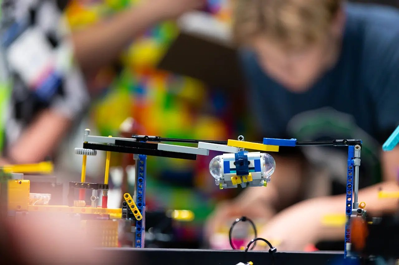 FIRST LEGO League robot with participant in background.